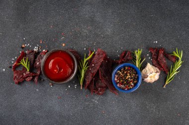 Kurutulmuş et, kurutulmuş et. Sağlıklı et atıştırmalıkları, servis panosunda sos ve baharatlar, kopyalama alanı.