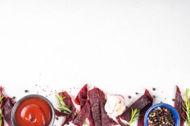 Kurutulmuş et, kurutulmuş et. Sağlıklı et atıştırmalıkları, servis panosunda sos ve baharatlar, kopyalama alanı.