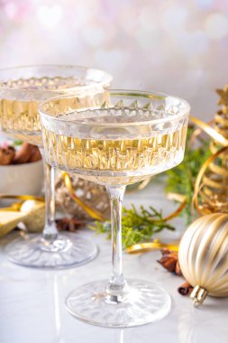 Noel süslemeli arka planda iki şampanya kadehi, Mutlu Noeller ve yeni yıl tebrik kartı geçmişi, altın takılar ve köknar ağacı dallarıyla