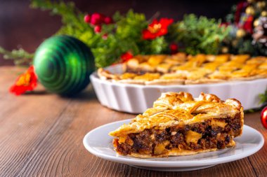 Geleneksel İngiliz Noel turtası. Ev yapımı tatlı kıymalı tart kek, baharatlı meyve, fındık ve elmalarla dolu, rahat ahşap masa üzerinde Noel ağacı ve süslemesi ile