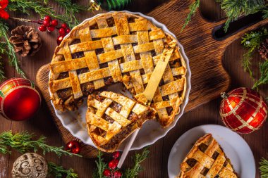 Geleneksel İngiliz Noel turtası. Ev yapımı tatlı kıymalı tart kek, baharatlı meyve, fındık ve elmalarla dolu, rahat ahşap masa üzerinde Noel ağacı ve süslemesi ile