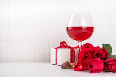 Kırmızı güller, şarap, hediye kutusu ve çikolatalı şekerlerle dolu sevgililer günü arkaplanı.
