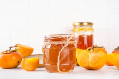 Hurma reçeli. Tatlı sonbahar reçeli ya da reçel reçeli kavanozda reçel reçel reçeli ve arka planda bütün ve kesim hurma c ile reçel konservesi