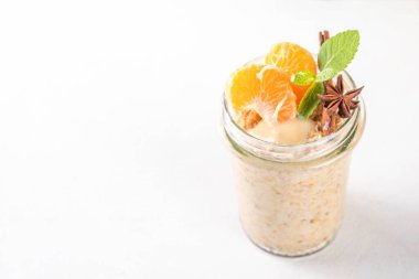 Mandalina kremalı bir gecelik yulaf ezmesi, kremalı yulaf ezmesi ve taze mandalina dilimleri, baharatlar ve portakal kabuğu.