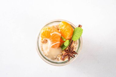 Mandalina kremalı bir gecelik yulaf ezmesi, kremalı yulaf ezmesi ve taze mandalina dilimleri, baharatlar ve portakal kabuğu.