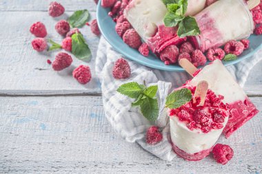 Sweet and tasty diet summer dessert. Homemade raspberry yogurt popsicle with fresh raspberries and mint. Healthy ice cream recipe. Wooden white background copy space clipart