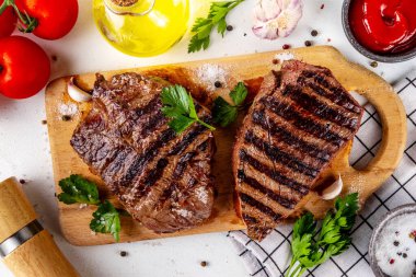 Ahşap kesme tahtasında ızgara biftek, ketçap sosu ve baharat, üst görünüm kopya alanı.