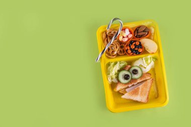 Cadılar Bayramı komik çocuklar, krakerli okul yemeği, sağlıklı peynirli sandviç, kurabiye ve ikramlar, parlak renkli arka plan fotokopi alanı üst görünümü.