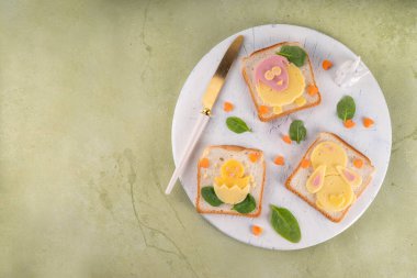 Çocukların kahvaltısı için yaratıcı ev yapımı Paskalya sandviçleri. Paskalya sembolleri şeklinde komik sandviçler - koyun, tavuk, tavşan, kızarmış ekmek, peynir, sosis, ıspanak ve havuçtan yapılır.