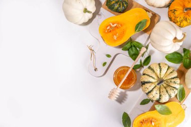 Bal kabakları değişik boyutlarda, çeşitli boyut ve renklerde kabaklar, bitki ve baharatlar, zeytin yağı, bal, beyaz mutfak masası arka planında üst görünümde fotokopi alanı 