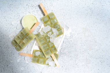 Vejetaryen kiraz yeşil buzlu çay. Vejetaryen diyeti hindistancevizi matcha latte dondurma lolipopları beyaz masa arkasında 