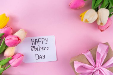 Anneler gününde lale çiçeği buketi, pembe kurdeleli hediye kutusu ve mutlu anneler günü etiketi. Tebrik kartı arkaplanı, poster, broşür, broşür, tanıtım malzemeleri, web sitesi