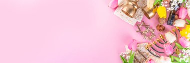 Passover, Pesah background. jewish Easter Passover spring holiday celebration, with accessories - menorah, matzo, spring flowers, wine bottle, gold wine glass, jewish david stars, copy space top view 