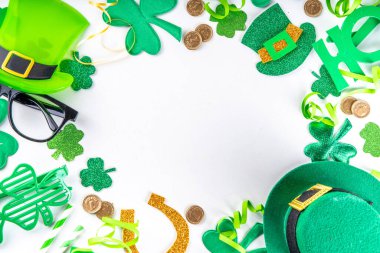 St Patrick holiday flatlay background with shamrock clover leaves, leprechaun hat decor, golden coin, party accessories, symbols of Patrick day