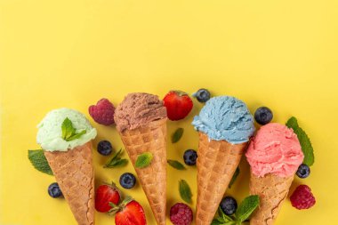  Parlak arka planda waffle külahlı renkli parlak dondurma. Taze böğürtlenli farklı dondurma külahları üst görünüm fotokopi alanı arka planı