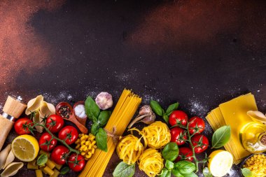 Baharatlı makarna ve yemek pişirmek için malzemeler. Hazırlık yemeği, öğle yemeği arkaplanı taze fesleğen, domates, baharat, sarımsak ve farklı çeşitte İtalyan Akdeniz makarnası.