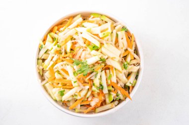 Elmalı, lahanalı, havuçlu ve taze soğanlı ev yapımı elma salatası. Sağlıklı sonbahar sebze salatası yoğurt soslu, porsiyonlu kaseler halinde mutfak masasında. 