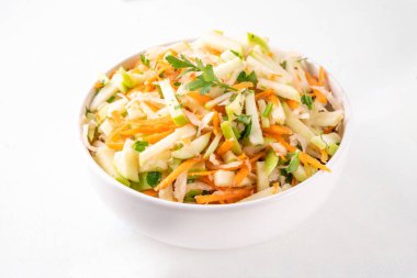 Elmalı, lahanalı, havuçlu ve taze soğanlı ev yapımı elma salatası. Sağlıklı sonbahar sebze salatası yoğurt soslu, porsiyonlu kaseler halinde mutfak masasında. 