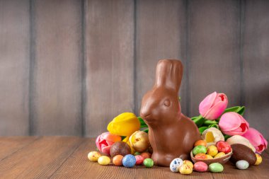 Paskalya arkaplan tebrik kartı, geleneksel şekerleme, Paskalya yumurtası avı eğlence konsepti. Çikolata tavşanı, çikolata ve şeker Tahta arka planda Paskalya yumurtası