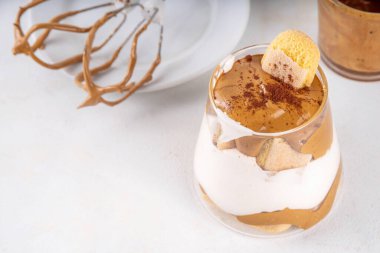 Moda dalgona tiramisu tatlısı. İki bardak kremalı kremalı kahve tiramisu, üzerine de hazır kahve köpüğü ve savoyardi.