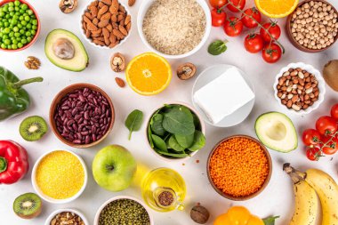 Portföy diyeti, fındık, sebze proteini, bitki sterolleri, yapışkan lif, fasulye, baklagiller, taze sebzeler ve beyaz arka plandaki meyveler dahil olmak üzere dengeli kolesterol vejetaryen gıdalar.