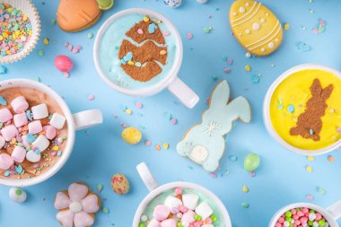 Paskalya partisi, kahvaltı, öğle yemeği için sıcak tatlı içecekler. Paskalya menüsü. Pembe, sarı, mavi, kahverengi, lokum kaplı sıcak çikolata bardakları, çikolatalı tavşan, latte yüzeyinde paskalya yumurtaları.
