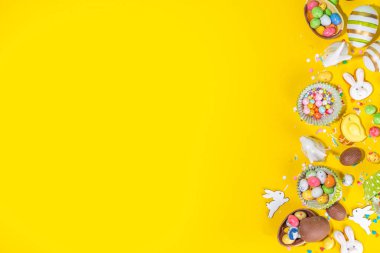 Yüksek renkli Paskalya pastası arka planı, Paskalya indirimi, parti davetiyesi deri yüzme, renkli Paskalya yumurtaları, çikolata yumurtaları ve parlak sarı arka plan manzaralı şeker parçacıklı tavşan fotokopi alanı