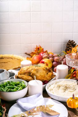 Thanksgiving family party  dinner table setting with plates, cutlery, glasses, traditional dishes - baked turkey or chicken, pumpkin pie, fruits, mashed potatoes, green beans, wooden background clipart