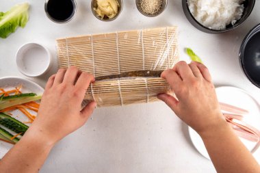 Geleneksel Kore kimbap 'ı, jambon, sebze ve marullu. Yemek pişirme, ev yapımı kimbap pişirme, aşama aşama pişirme ve kesme ellerini resimde kesme, üst görünüm