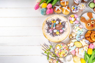 Easter brunch, breakfast food, Kids Easter party buffet. Various traditional Easter sweets, candy, pasties and baking - cross buns, cheesecake, chocolate eggs, pancakes, cupcakes, top view copy space