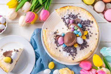 Homemade Easter cheesecake, sweet cottage cheese baking, with Ester chocolate eggs and chocolate drops, with holiday decorations and spring flowers