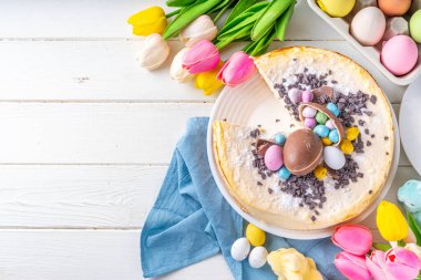 Homemade Easter cheesecake, sweet cottage cheese baking, with Ester chocolate eggs and chocolate drops, with holiday decorations and spring flowers