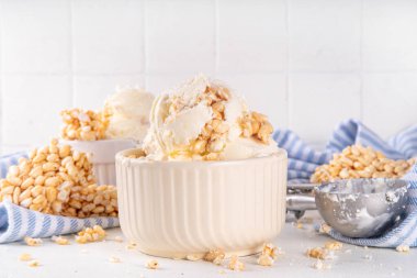 Pirinç gevreği dondurmayı, gevrek vanilyalı dondurmayı portakal kaselerinde, beyaz masa arkasında bolca pirinç gevreğiyle ikram eder.