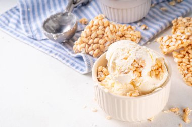 Pirinç gevreği dondurmayı, gevrek vanilyalı dondurmayı portakal kaselerinde, beyaz masa arkasında bolca pirinç gevreğiyle ikram eder.