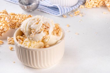 Pirinç gevreği dondurmayı, gevrek vanilyalı dondurmayı portakal kaselerinde, beyaz masa arkasında bolca pirinç gevreğiyle ikram eder.