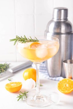 Mandalina Gin-tini kokteyli, buzlu alkollü kış içeceği cin, taze portakal mandalini (mandalina) ve biberiye filizi, beyaz masa arkaplan fotokopi alanı üzerinde.