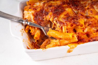Fırınlanmış Ziti makarnası bolonez ya da marinara domates sosu ve peyniri, fırında tava ve tabakta, beyaz mutfak masasında fotokopi alanı.