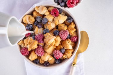 Tiny breakfast croissants cereals with fresh berries and milk. Bowl portions with trendy fresh baked mini petite croissants with raspberry and blueberry, dessert morning snack clipart