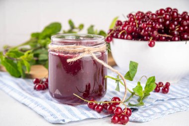 Mutfak masasında taze böğürtlen bulunan küçük kavanozdaki organik kırmızı frenk üzümü reçeli ya da marmelat.