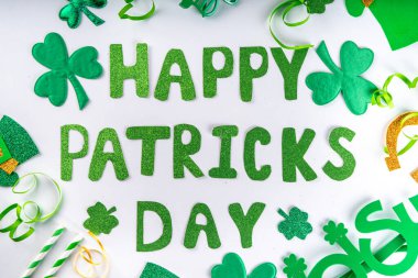 St Patrick holiday flatlay background with shamrock clover leaves, leprechaun hat decor, golden coin, party accessories, symbols of Patrick day