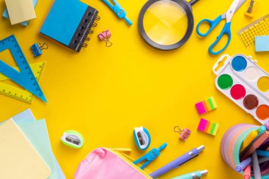 Okul ekipmanları parlak sarı düz yerde yatıyordu. Çeşitli okul ve ofis malzemeleri, aksesuarlar. Okul satışına geri dön. Üst görünüm kopyalama alanı