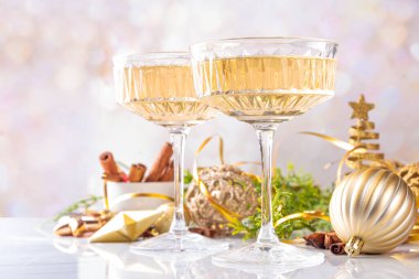 Noel süslemeli arka planda iki şampanya kadehi, Mutlu Noeller ve yeni yıl tebrik kartı geçmişi, altın takılar ve köknar ağacı dallarıyla