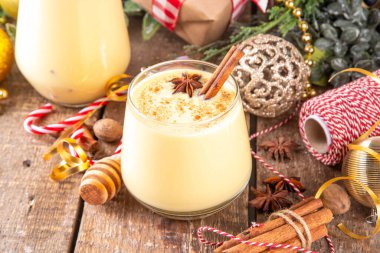 Tarçın çubukları ve anason yıldızlı Noel içeceği Noel 'de iki bardak klasik eggnog kokteyli köknar ağacı ve mücevherlerle süslenmiş yeni yıl arkaplanı.