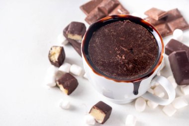 Marzipan sıcak çikolatası, içinde malzemeler, şekerlemeler ve badem ezmesi çikolataları olsun. Kış ve Noel rahatlığı Lezzetli sıcak kakao beyaz bardakta