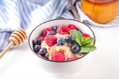 Taze dutlu yulaf ezmesi ve bal. Ahududu, yaban mersini ve bal ile porsiyon kahvaltı yulafı. Sağlıklı dengeli sabah yemeği.