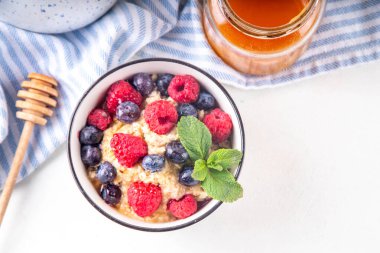 Taze dutlu yulaf ezmesi ve bal. Ahududu, yaban mersini ve bal ile porsiyon kahvaltı yulafı. Sağlıklı dengeli sabah yemeği.