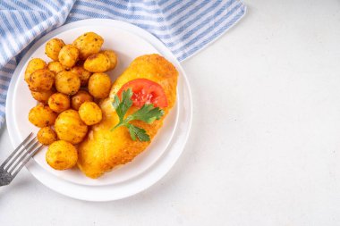 Kızarmış patates tarafı kızarmış tavuk pirzolası, servis tabağında, dengeli bir öğle yemeği. Sağlıksız yağda kızartılmış yiyecekler