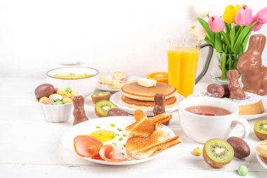 Paskalya tatili tatlı kahvaltı, brunch. Paskalya süslü Belçika waffle 'ları, krepler, kahvaltı gevrekleri ve süt, kızarmış yumurtalar kızarmış ekmek ve pastırma, Paskalya çikolatalı yumurtalar ve bahar çiçekleriyle birlikte tavşan.