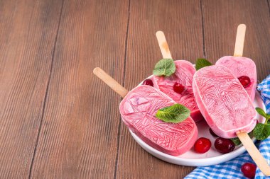 Yabanmersinli dondurma, dondurulmuş kremalı dondurma yoğurt ve böğürtlenli lolipoplar, beyaz tabakta, taze yaban mersinli ve nane yapraklı. 