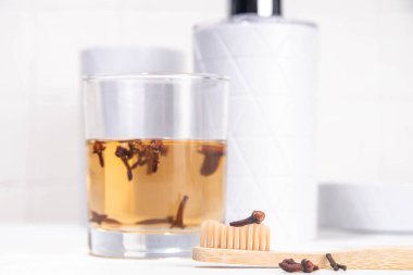 Clove Mouthwash with toothbrush on white table, Ayurvedic, antiseptic, anti-inflammatory and antioxidant Mouthwash, with organic Clove oil clipart